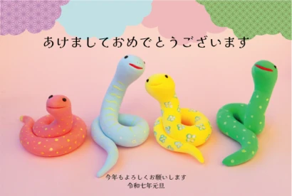 ピンク背景にたくさんの蛇の写真デザイン年賀状